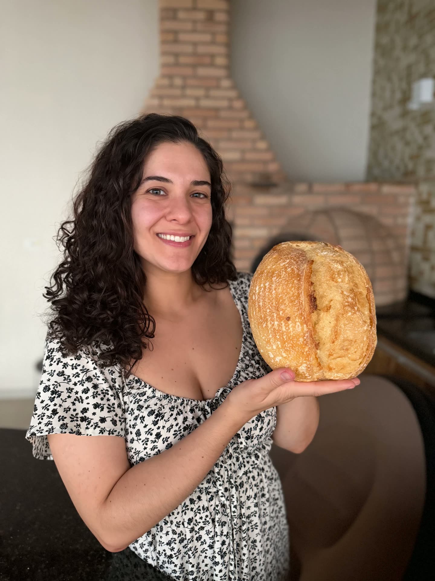 Gi sorrindo para a câmera segurando um pão de fermentação natural com as duas mãos